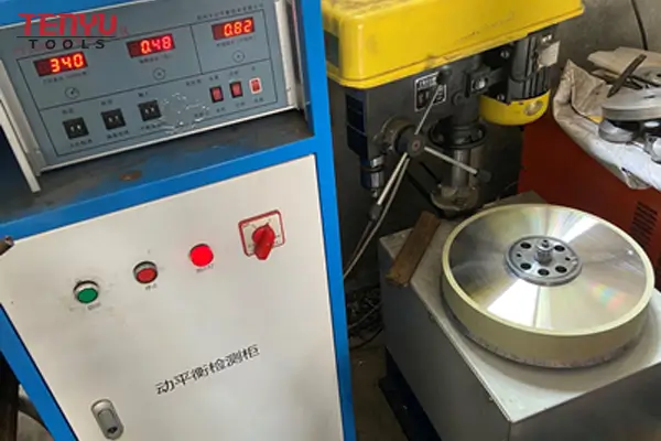 Technician performing a dynamic balance test on a grinding wheel