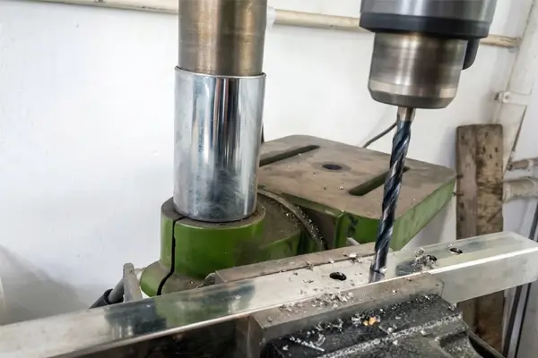 Close-up of black oxide drill bit cutting through metal