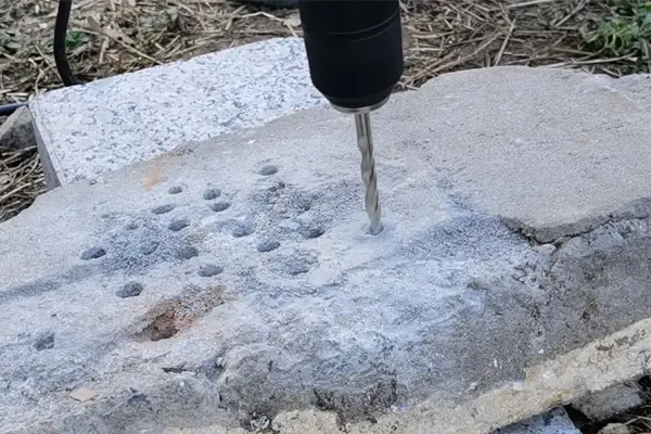 Cross-head masonry drill bit drilling into reinforced concrete