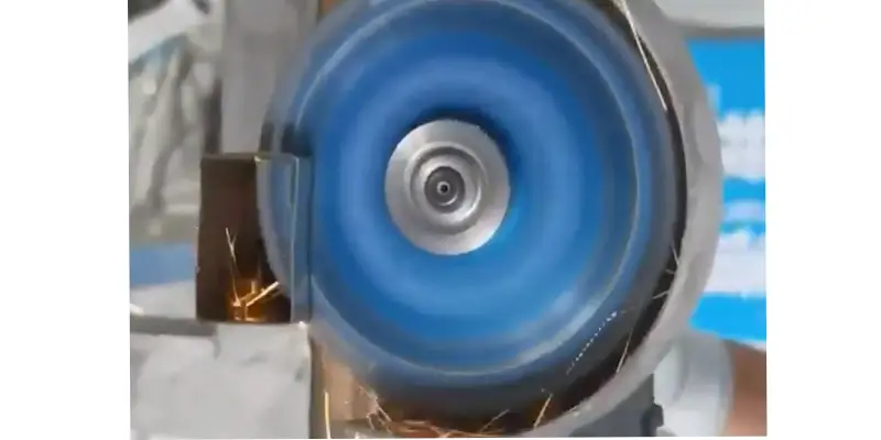 A professional metalworker using an angle grinder with a diamond blade on heavy steel piping